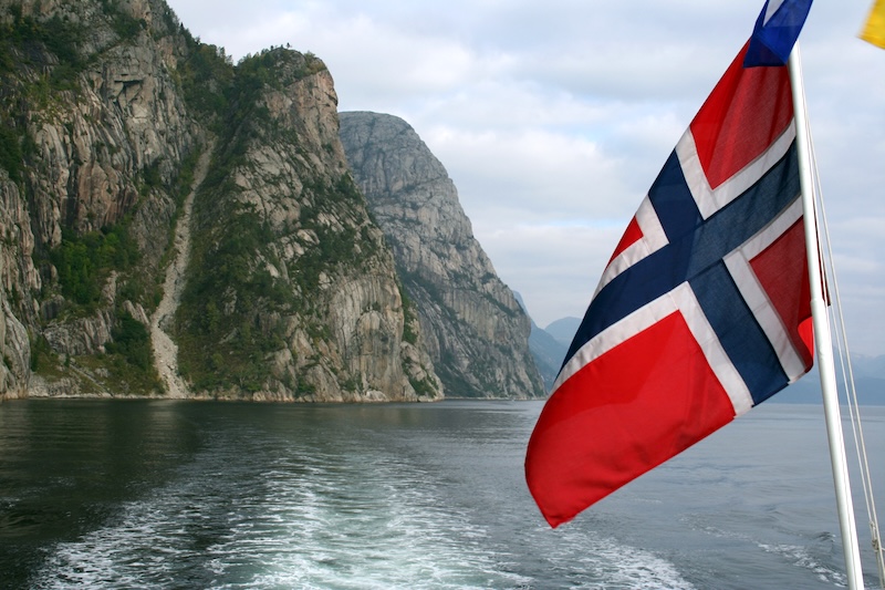 A fjord in Norway, with the Norwegian flag in the foreground